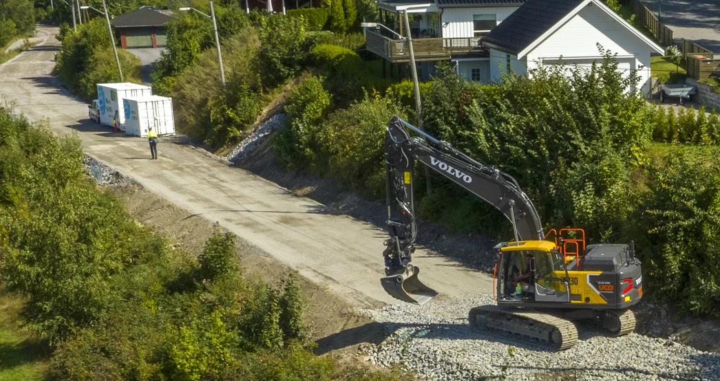 Elektrisk gravemaskin ved siden av et ladeanlegg