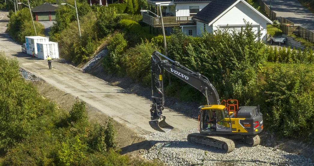 Elektrisk gravemaskin ved siden av et ladeanlegg