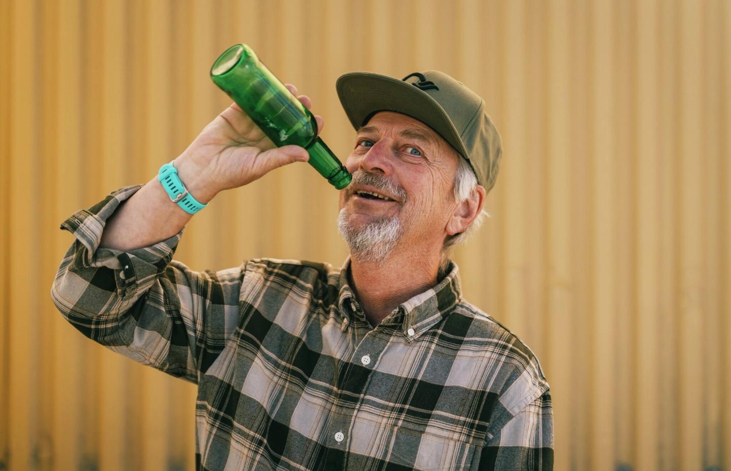 Mann later som han drikker fra en flaske som er tom.