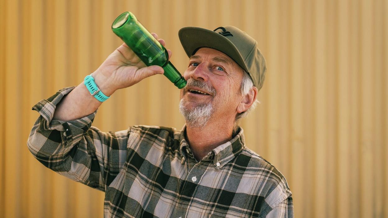 Mann later som han drikker fra en flaske som er tom.