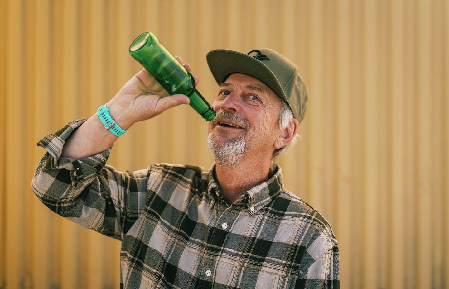 Mann later som han drikker fra en flaske som er tom.