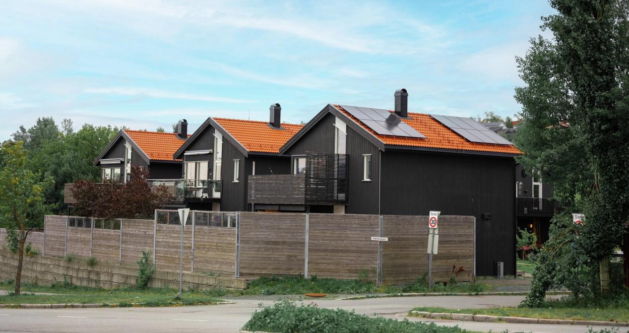 Tre identiske hus på rekke, der det nærmeste har installert solceller på taket