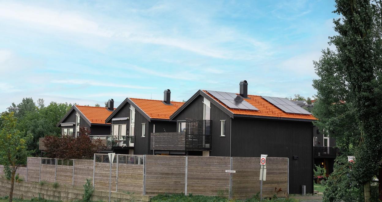 Tre identiske hus på rekke, der det nærmeste har installert solceller på taket