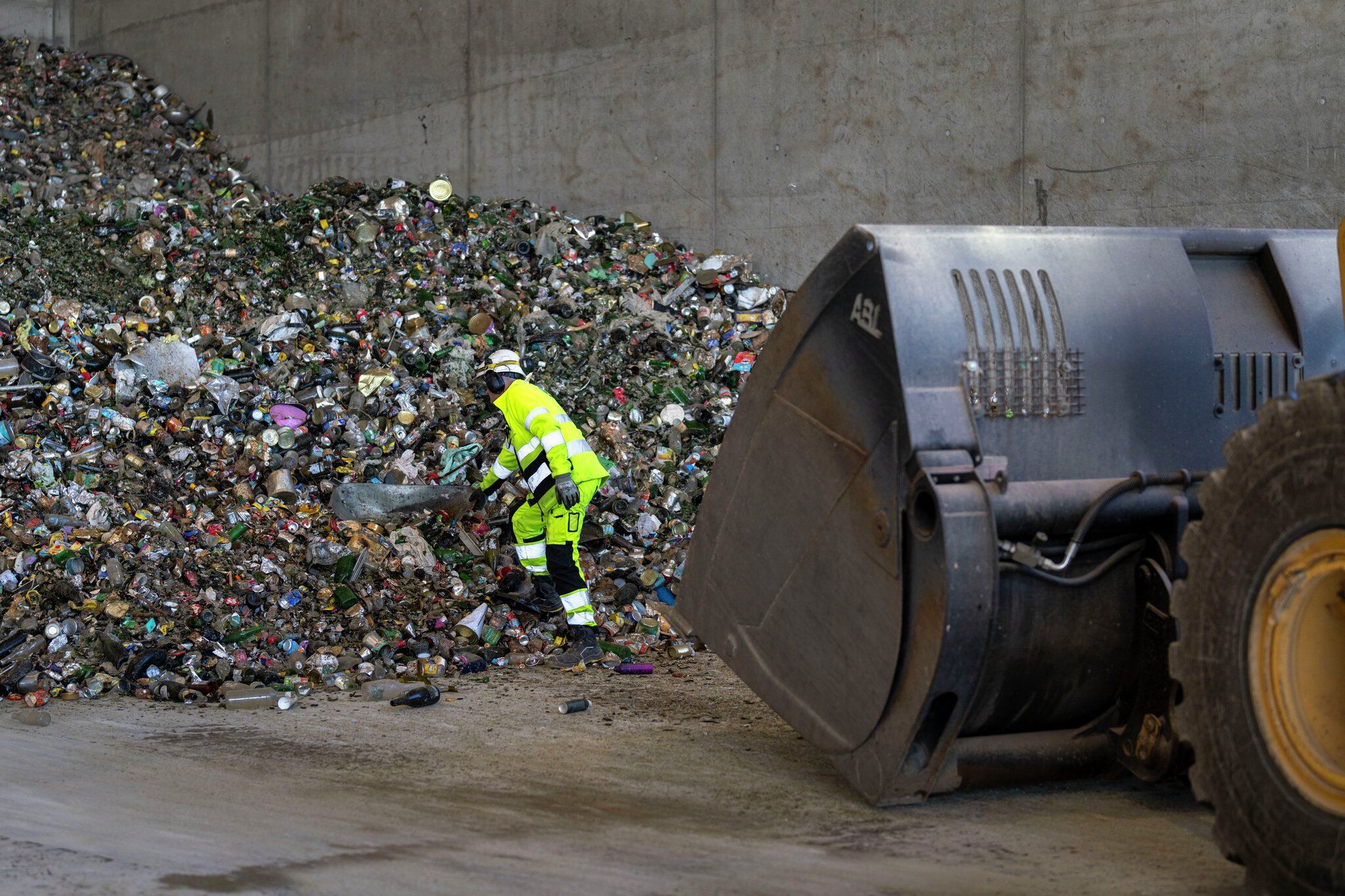 Mann henter ut trillebår fra en søppelhaug.