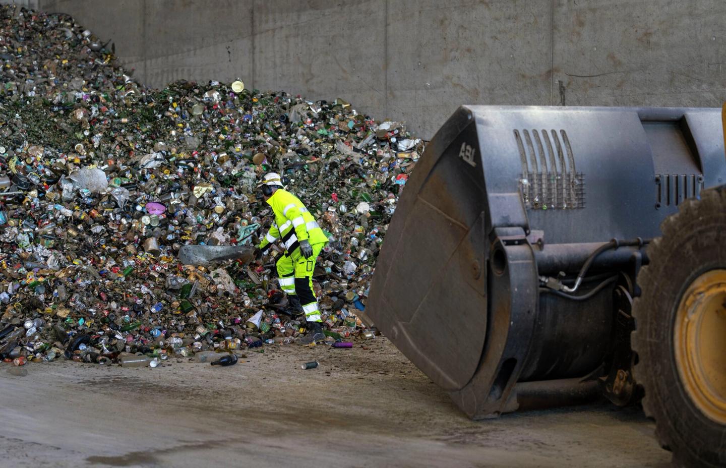 Mann henter ut trillebår fra en søppelhaug.