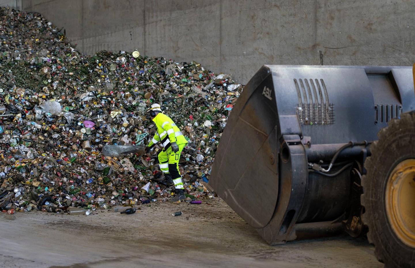 Mann henter ut trillebår fra en søppelhaug.