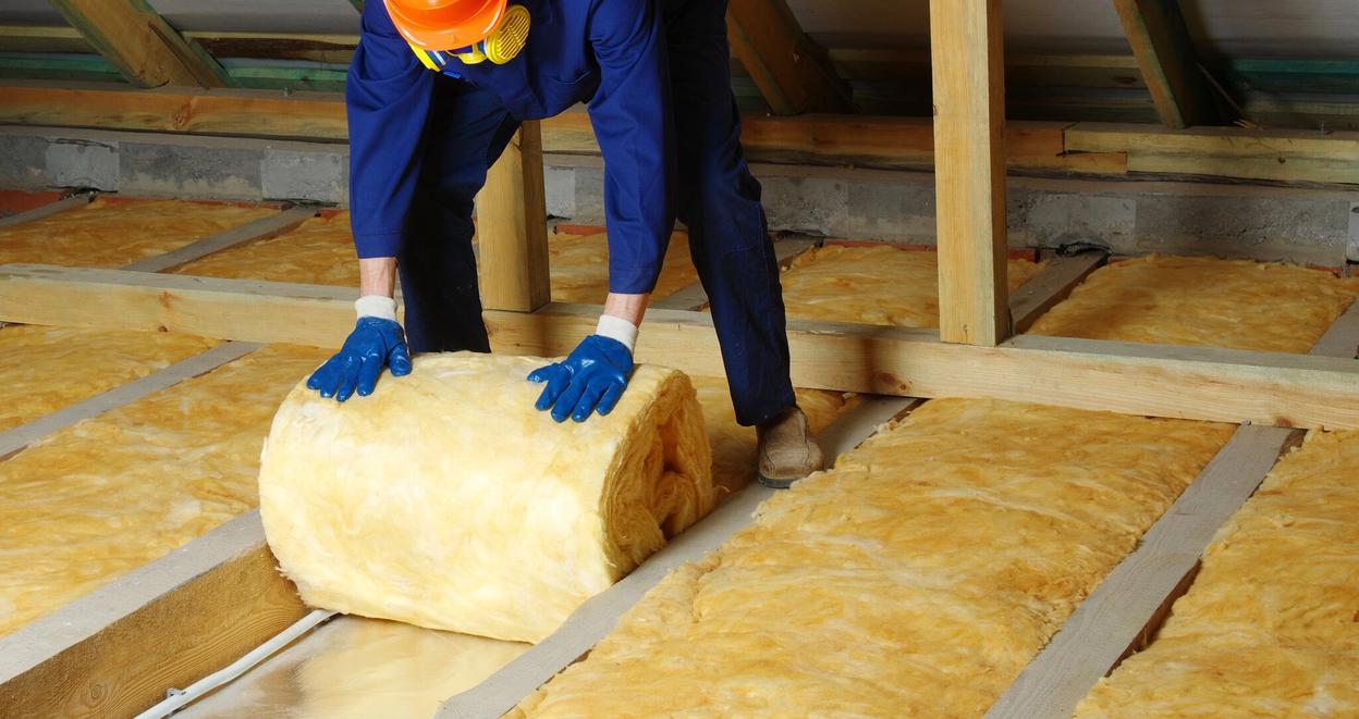 Håndverker ruller ut isolasjon på loft