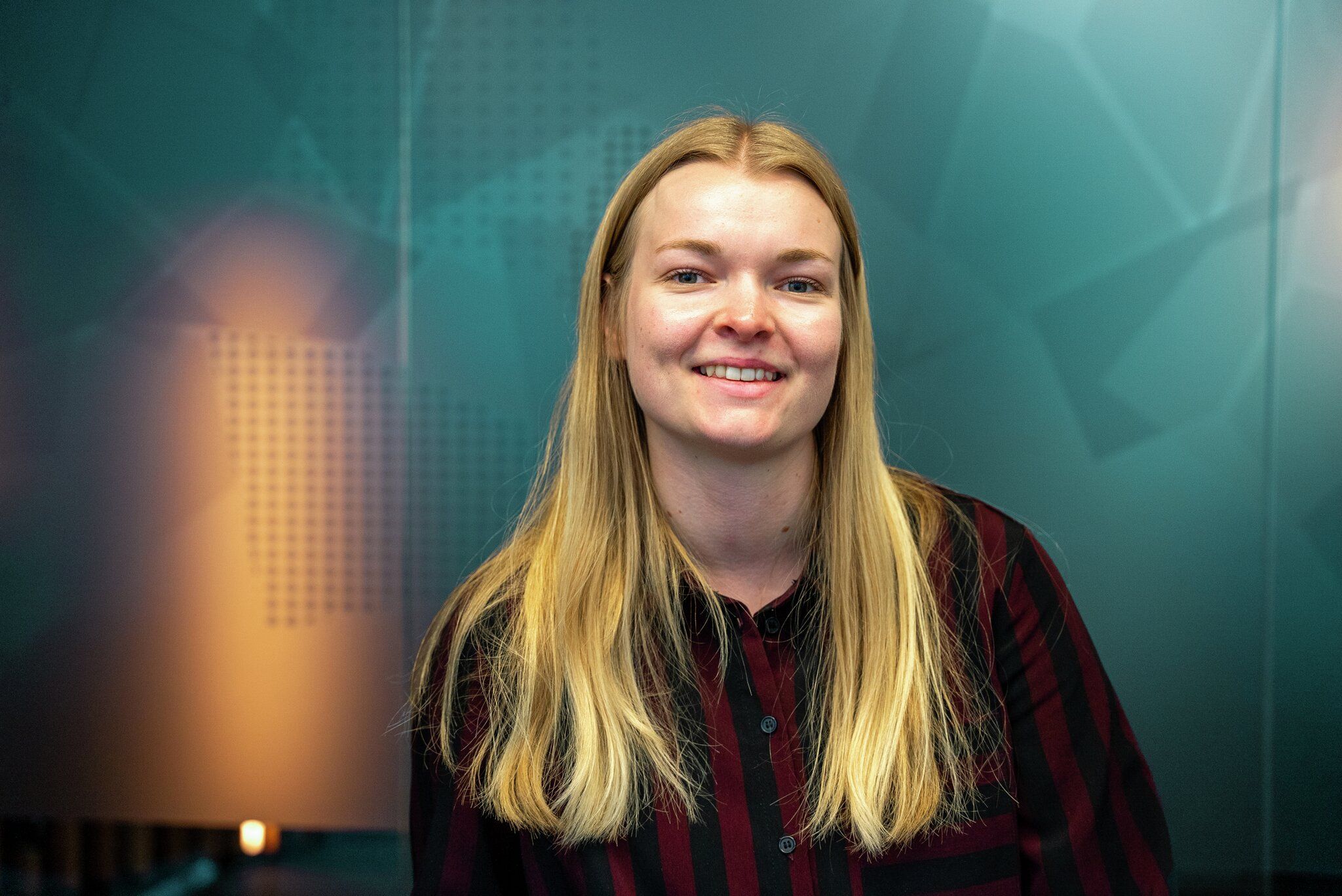 Portrett av ung kvinne foran en blå glassvegg