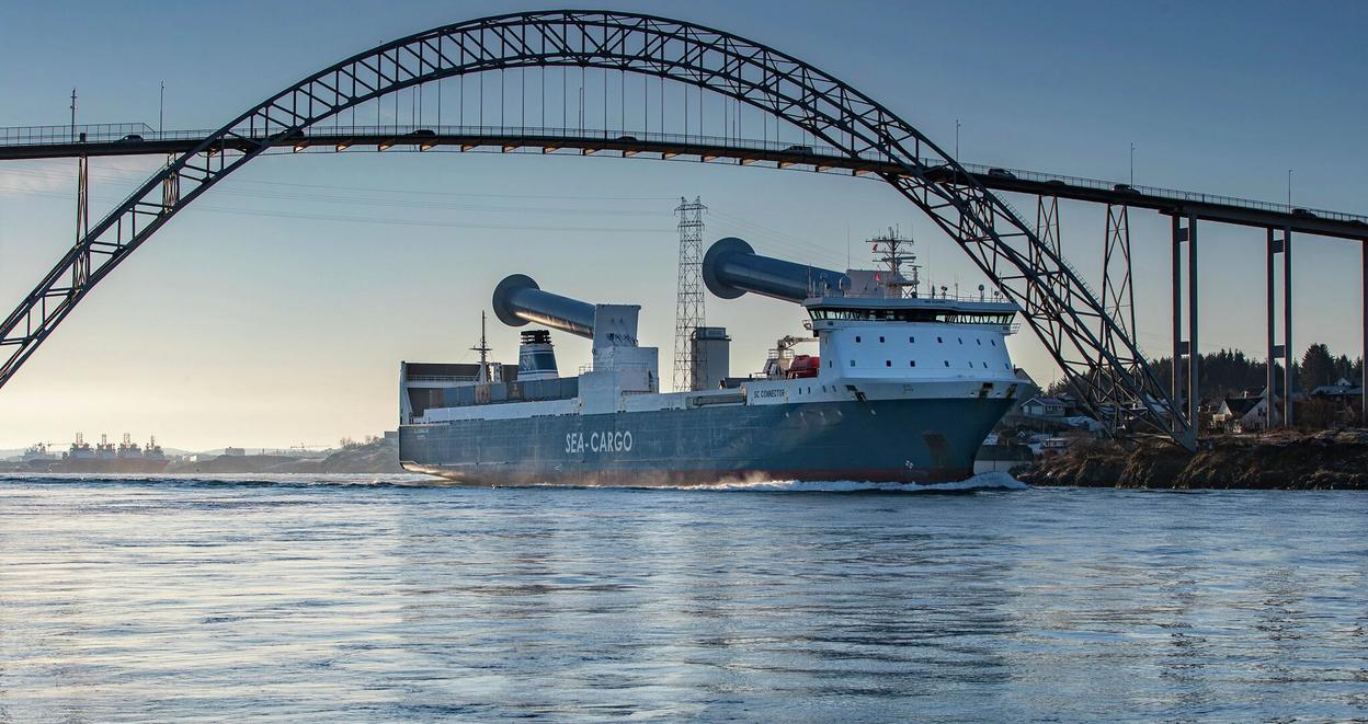 Skip med senkede rotorseil passerer under bro