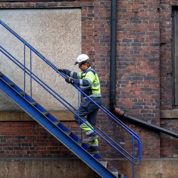 Arbeider går opp en blå trapp.