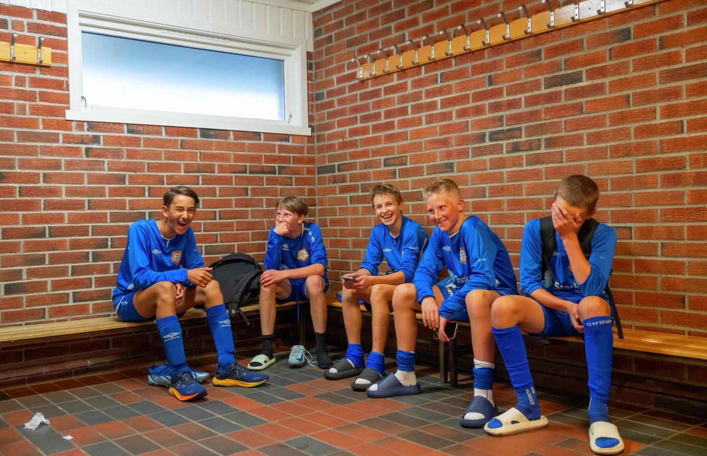 Gutter som spiller fotball sitter i garderoben.