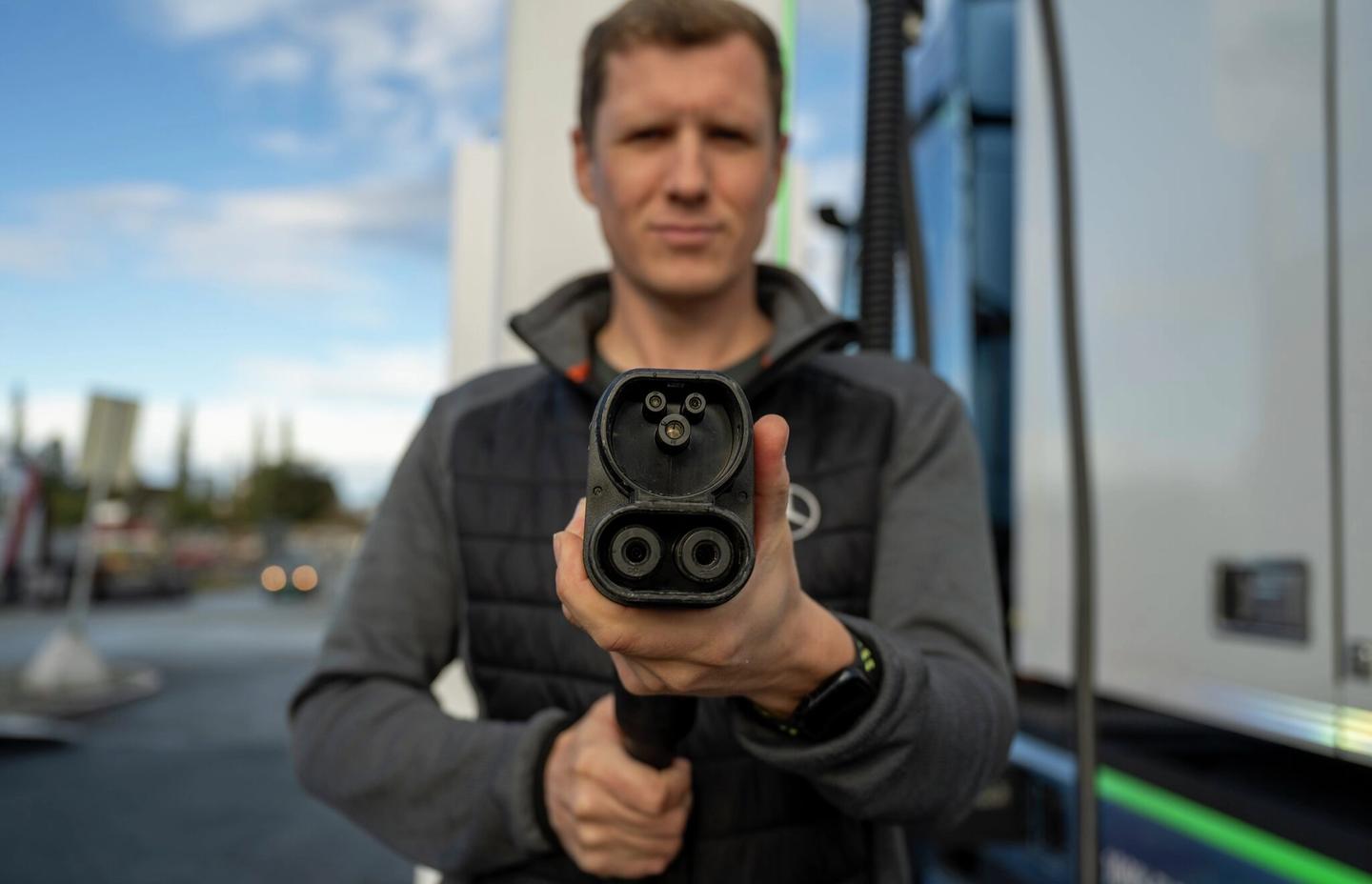 mann holder ladekabel i hånden.