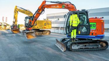 To elektriske gravemaskiner står utstilt ved en messe