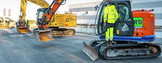 To elektriske gravemaskiner står utstilt ved en messe