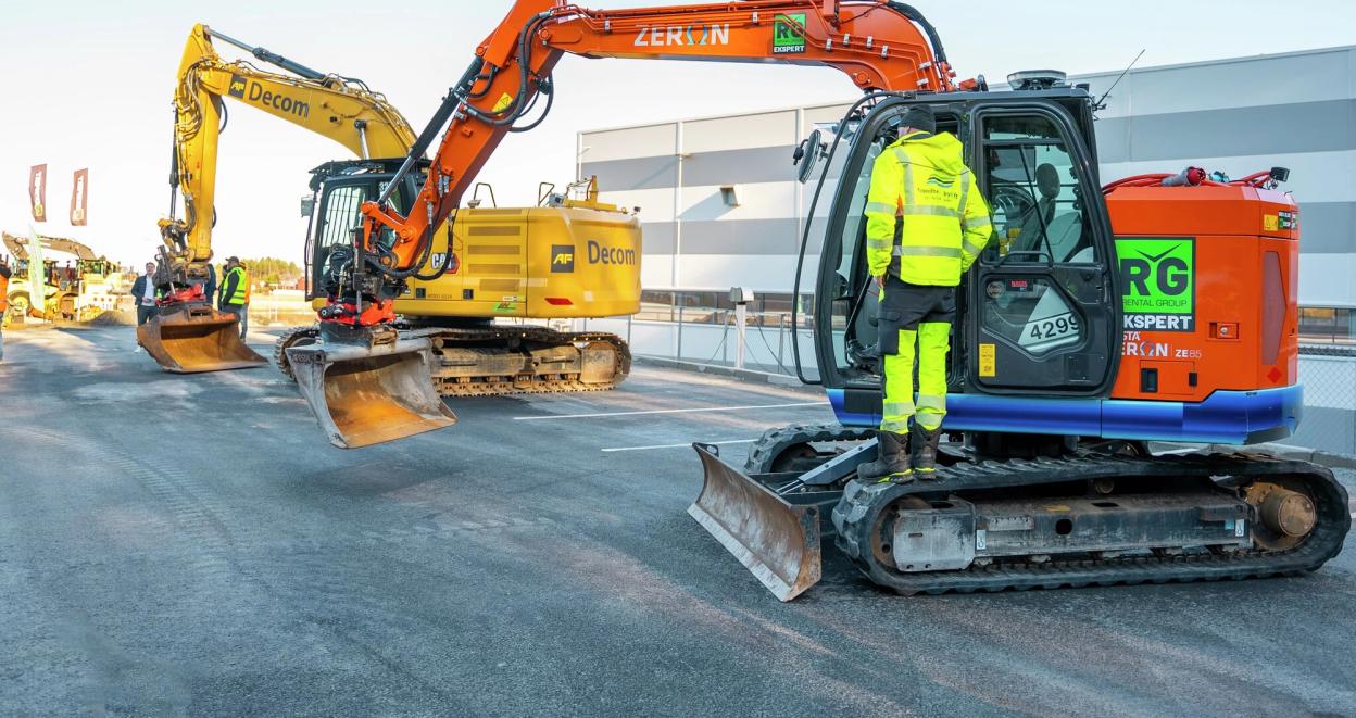 To elektriske gravemaskiner står utstilt ved en messe