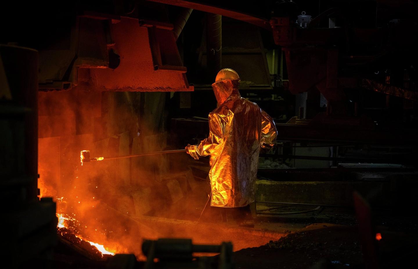 Mann i beskyttelsesutstyr tar prøver fra smelteovnen.