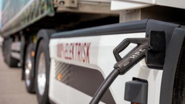 En elektrisk lastebil står med laderen koblet til