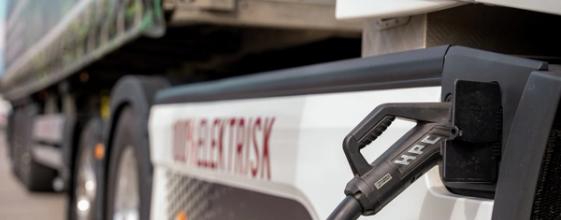 En elektrisk lastebil står med laderen koblet til