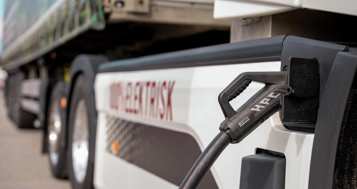 En elektrisk lastebil står med laderen koblet til