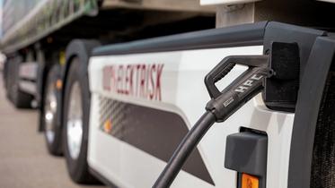 En elektrisk lastebil står med laderen koblet til