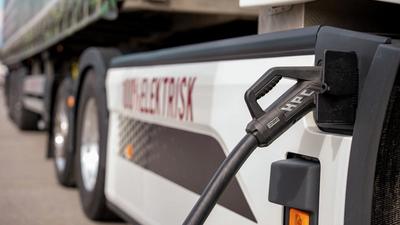 En elektrisk lastebil står med laderen koblet til