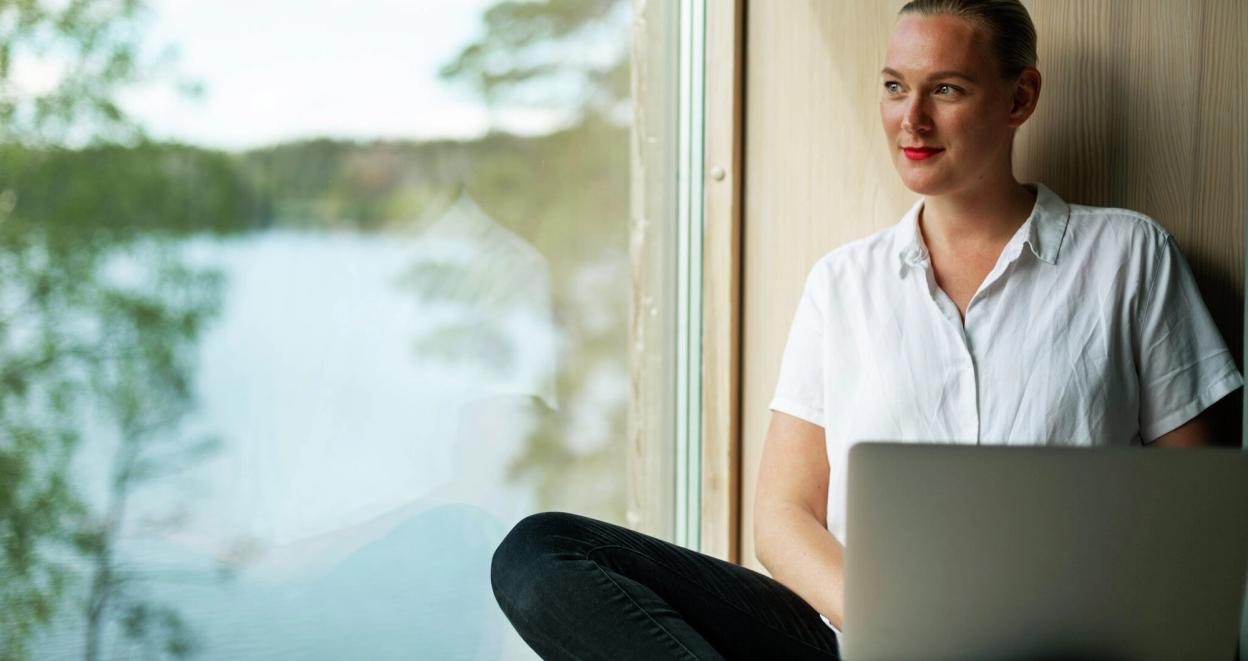Kvinne sitter i vinduet med pc