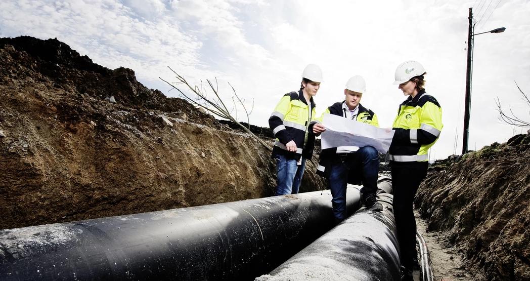 Ansatte undersøker plantegninger ved et anleggsområde