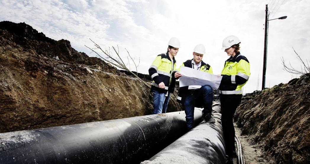 Ansatte undersøker plantegninger ved et anleggsområde