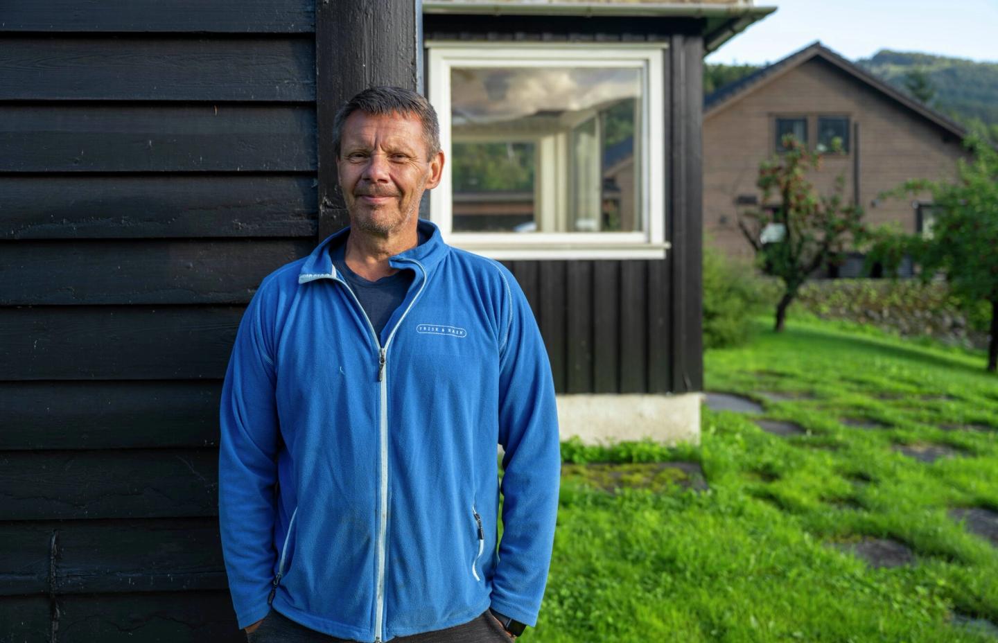 Mann står ved huset sitt.