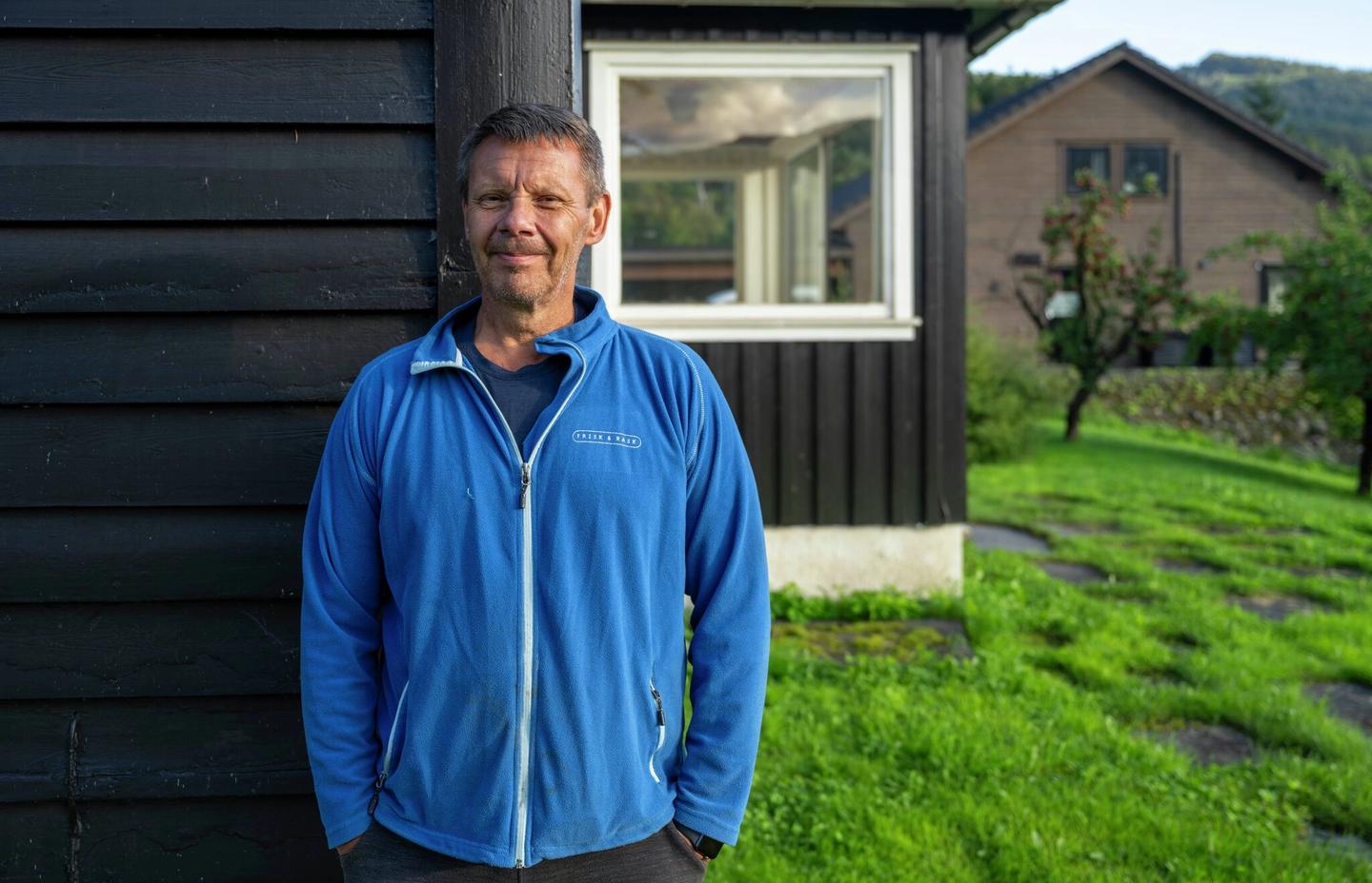 Mann står ved huset sitt.