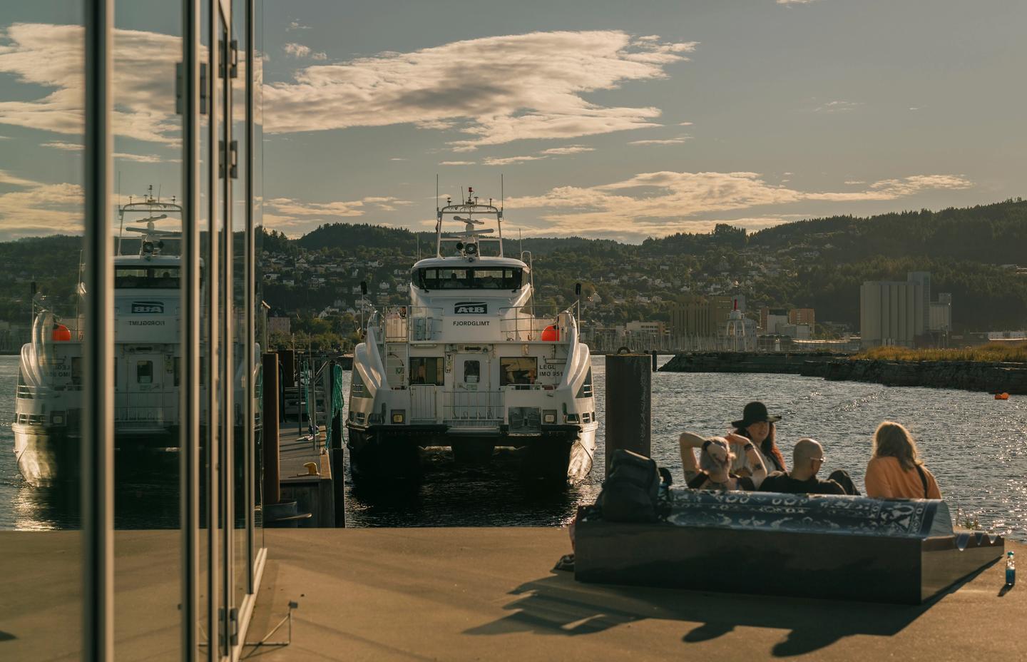 En gruppe venner sitter på ferjeleiet en varm sommerdag
