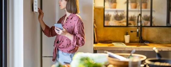 Boligeier som justerer innstilling på energistyringssystem