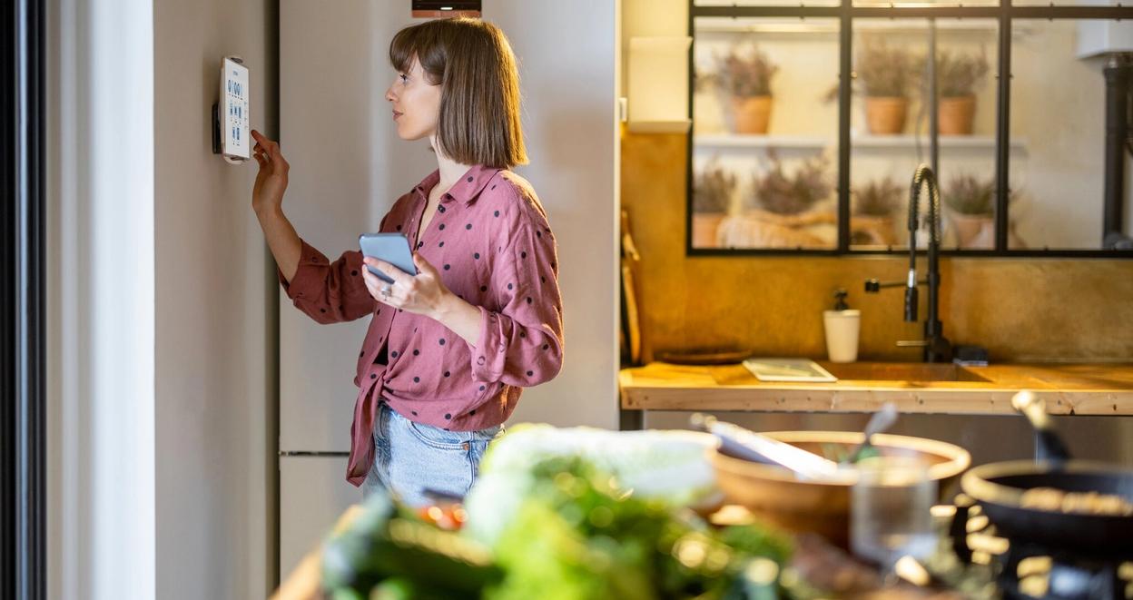 Boligeier som justerer innstilling på energistyringssystem