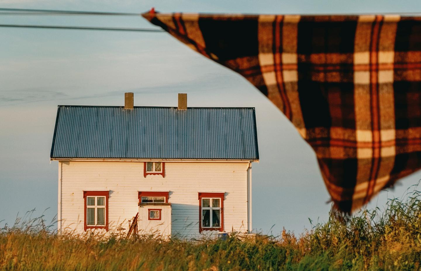 Et hvitt norsk kysthus en varm sommerkveld