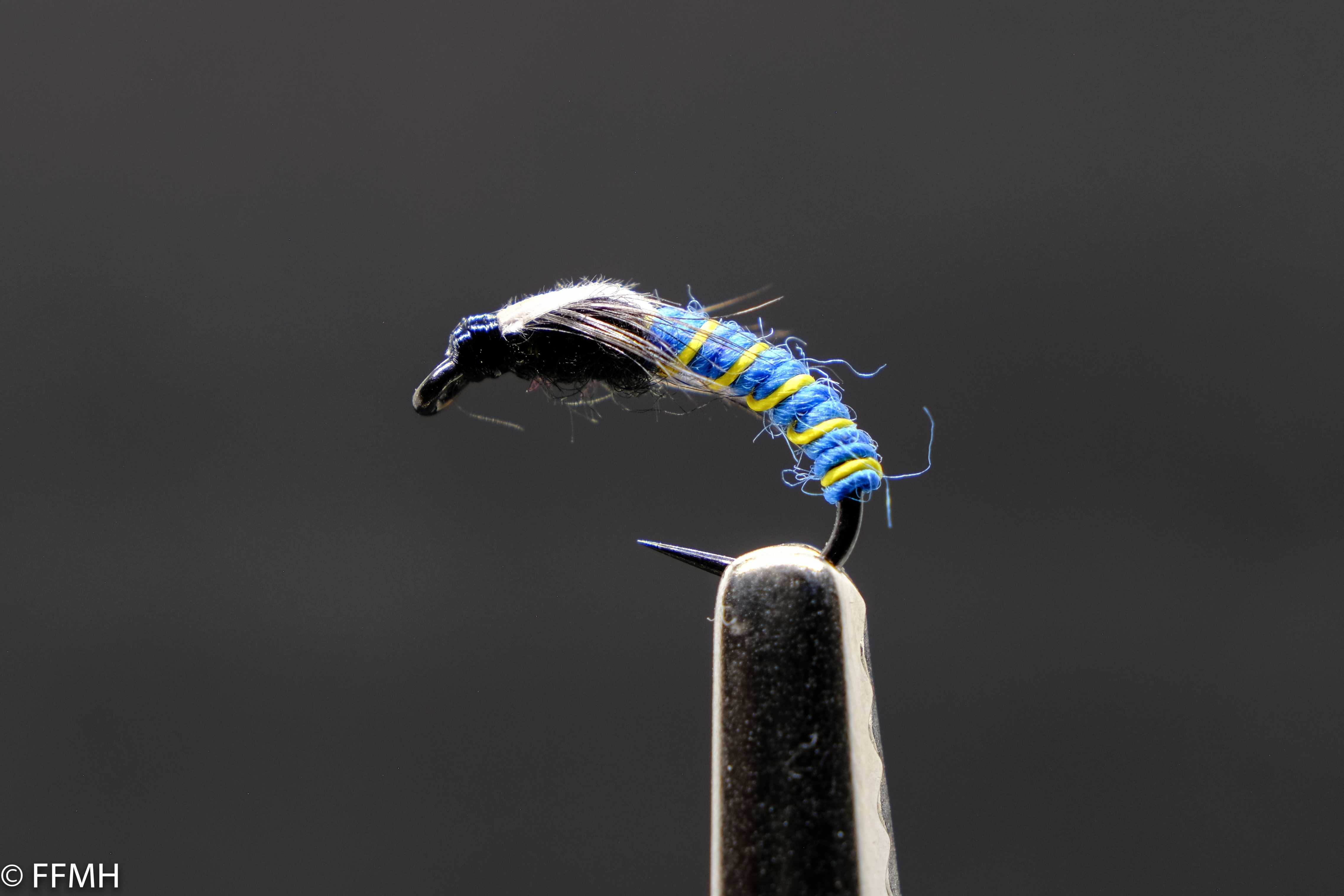 Jujubee Midge – handgebundene Midge-Nymphe mit leuchtenden blauen und gelben Segmenten, ideal für feines Fliegenfischen auf Äschen und Forellen in Stillgewässern