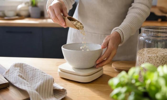 Oats being poured into a bowl on a kitchen scale