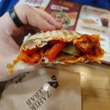 The seeker holding up a spicy kebab to show the hot sauce and other ingredients