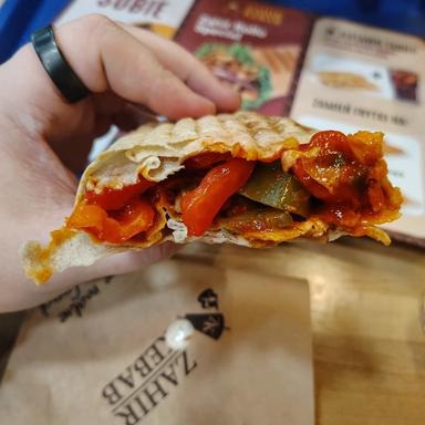 The seeker holding up a spicy kebab to show the hot sauce and other ingredients