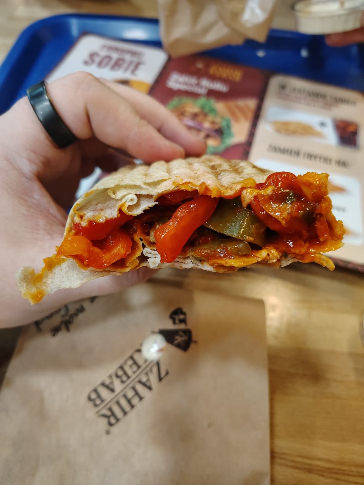 The seeker holding up a spicy kebab to show the hot sauce and other ingredients