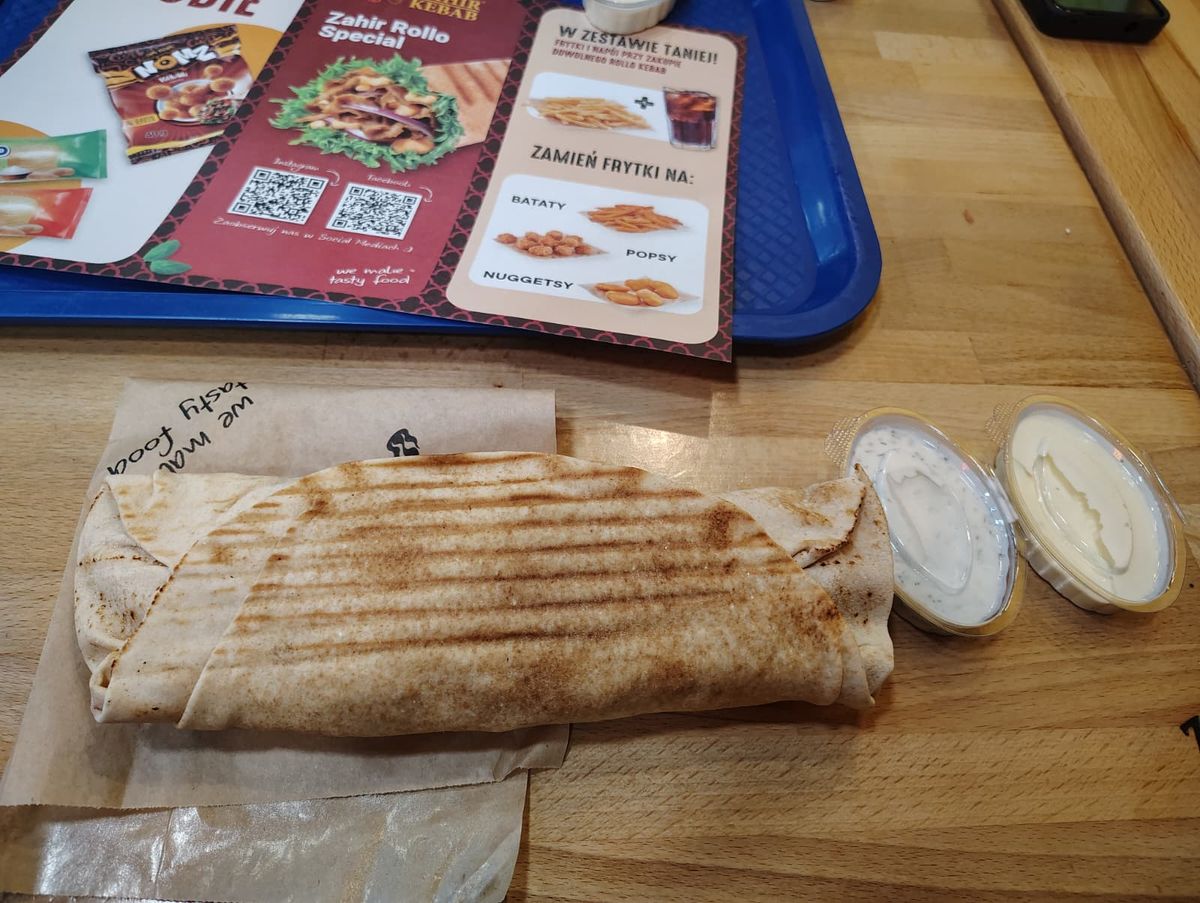 A kebab with yukfa bread sitting next to garlic and dill sauces in containers
