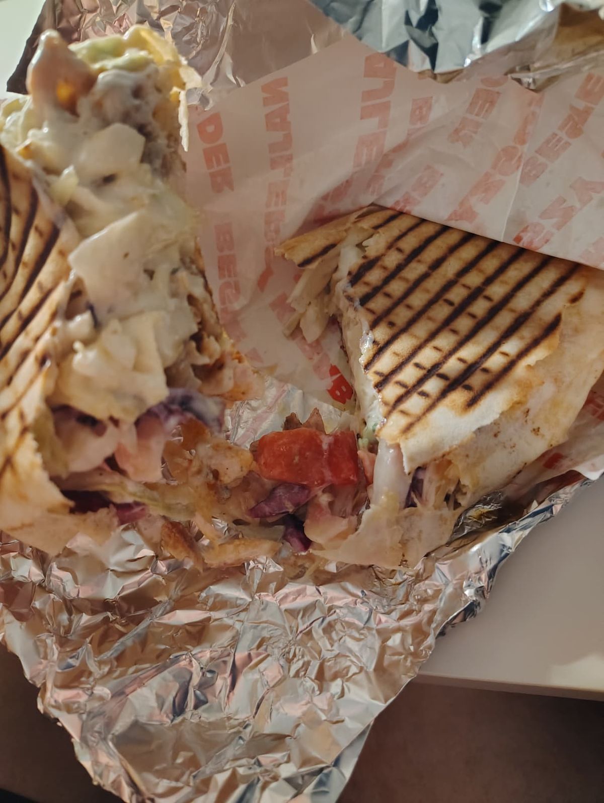 Semicircle kebab split in half showing the ingredients and sauce
