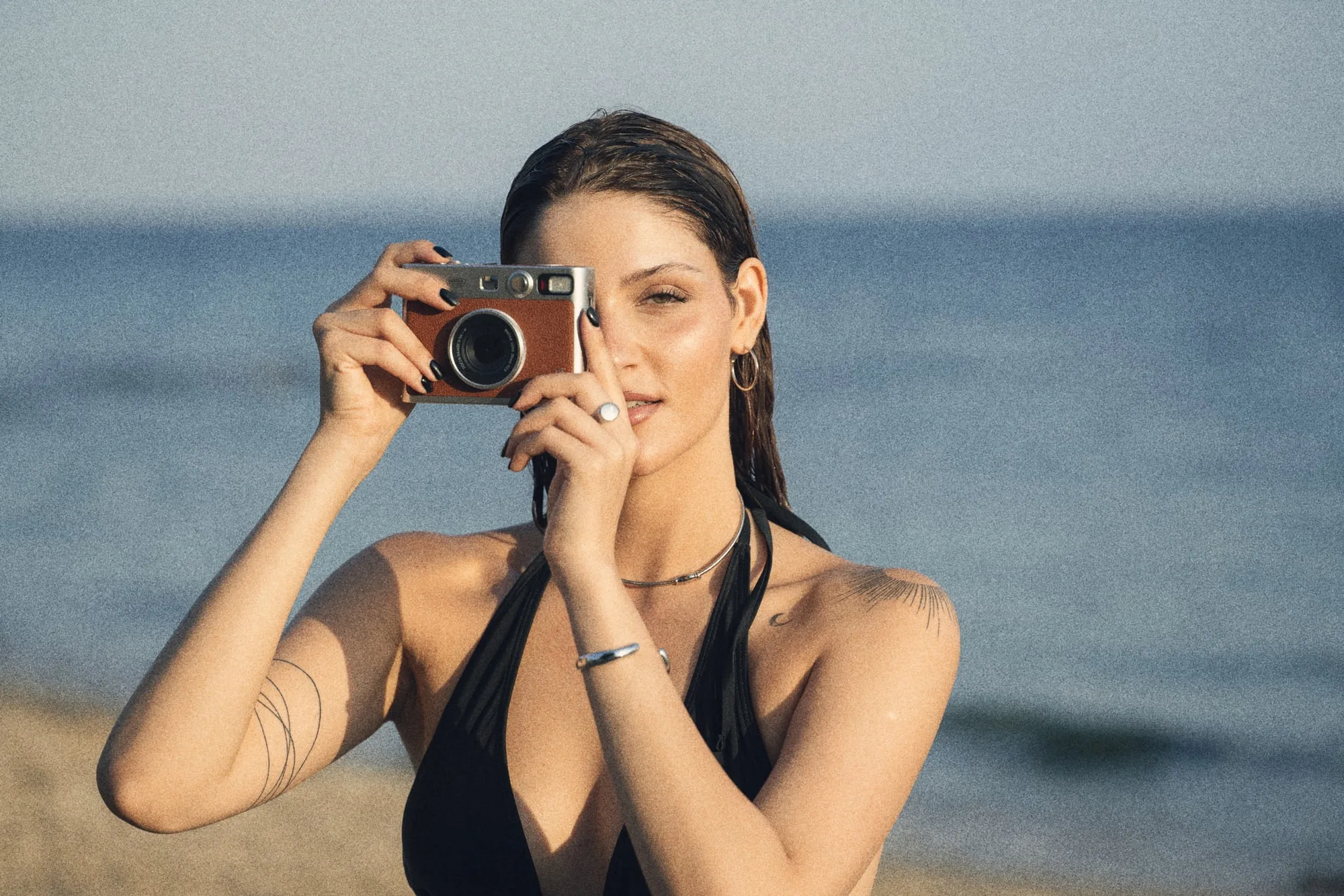 Woman on a beach holding a compact film camera