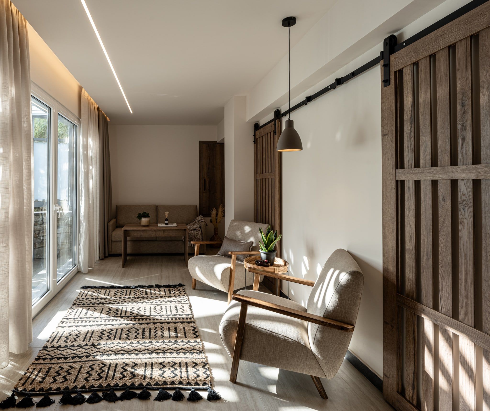 Hotel suite living area with two armchairs, a patterned rug and a sliding barn door