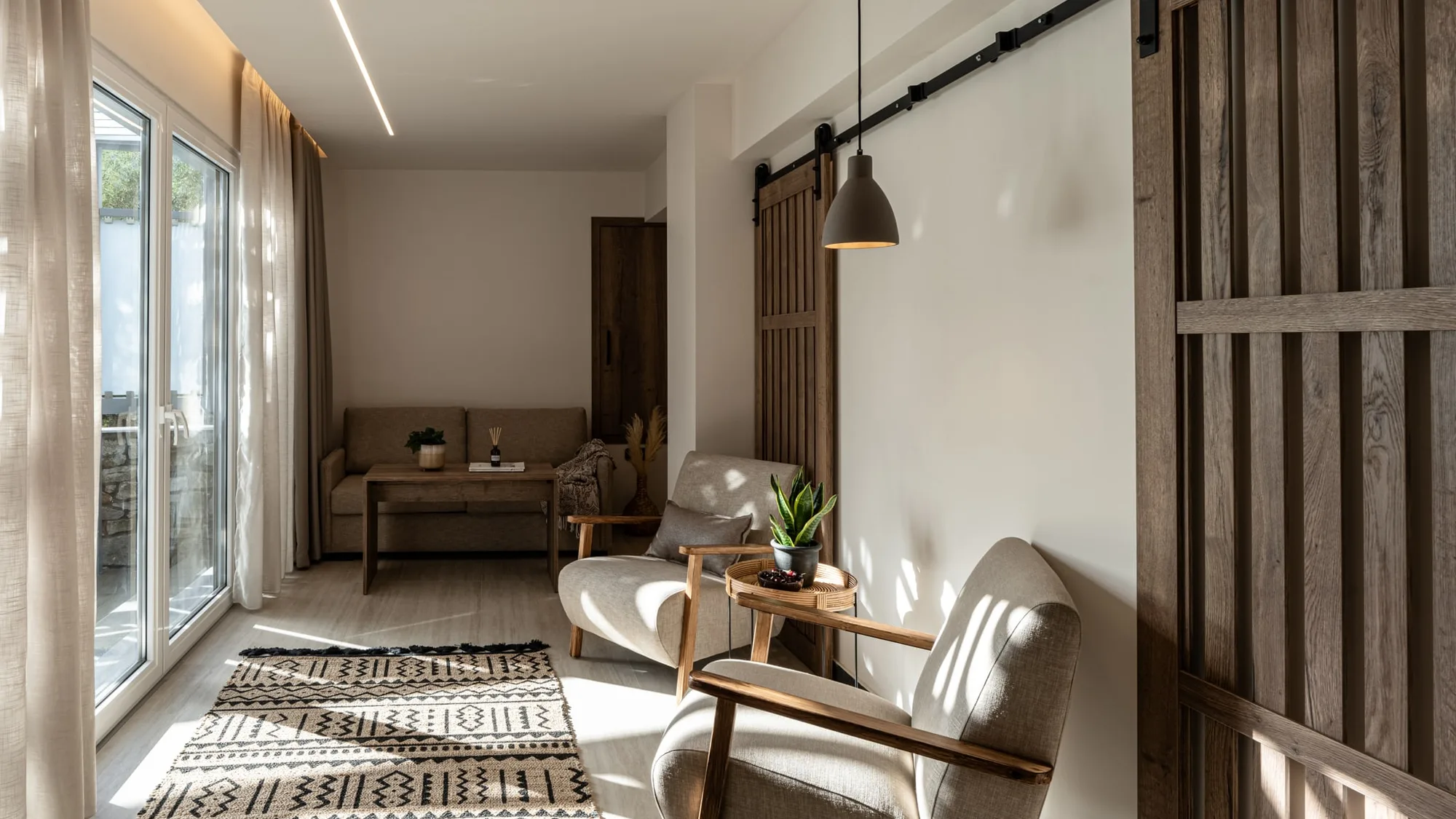 Hotel suite living area with two armchairs, a patterned rug and a sliding barn door