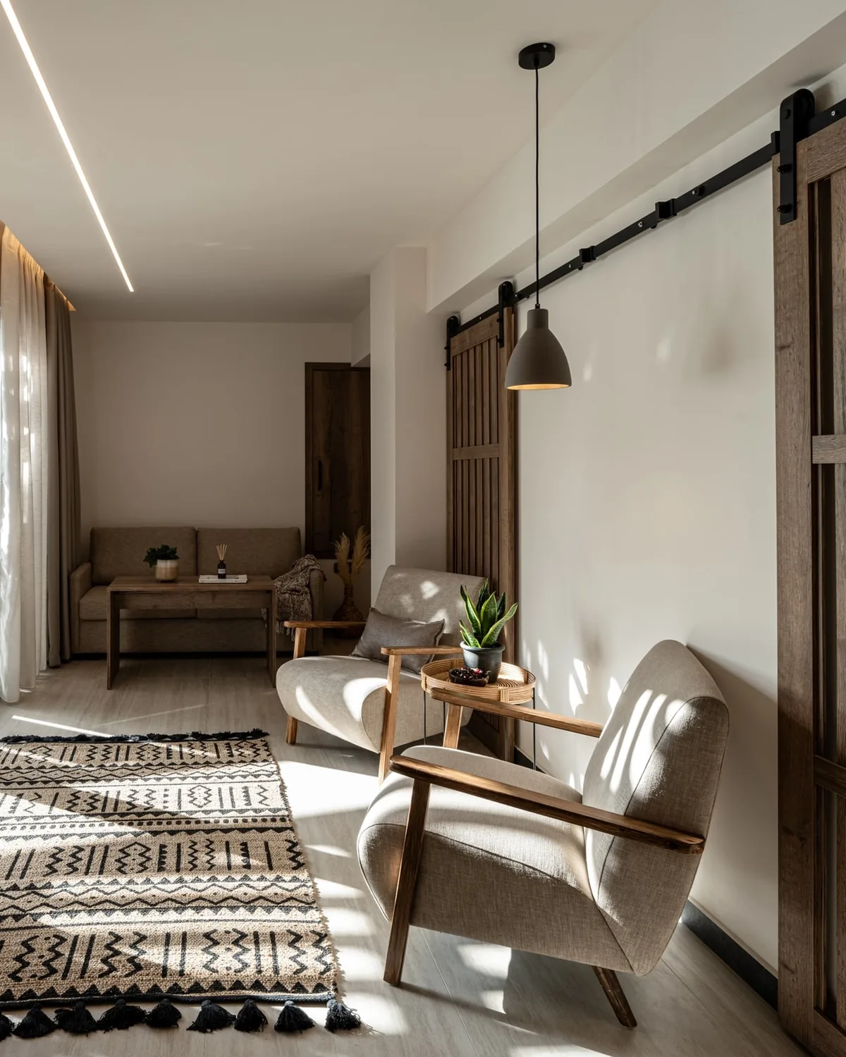 Hotel suite living area with two armchairs, a patterned rug and a sliding barn door