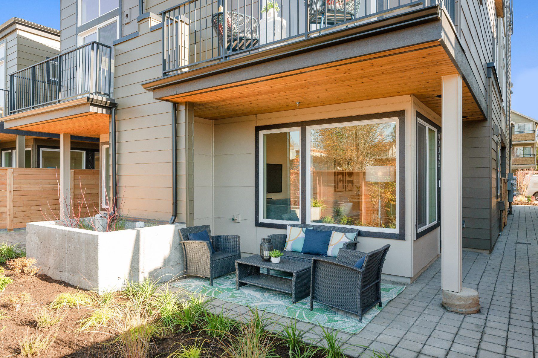 A covered patio off the main level, looking down the walkway between homes