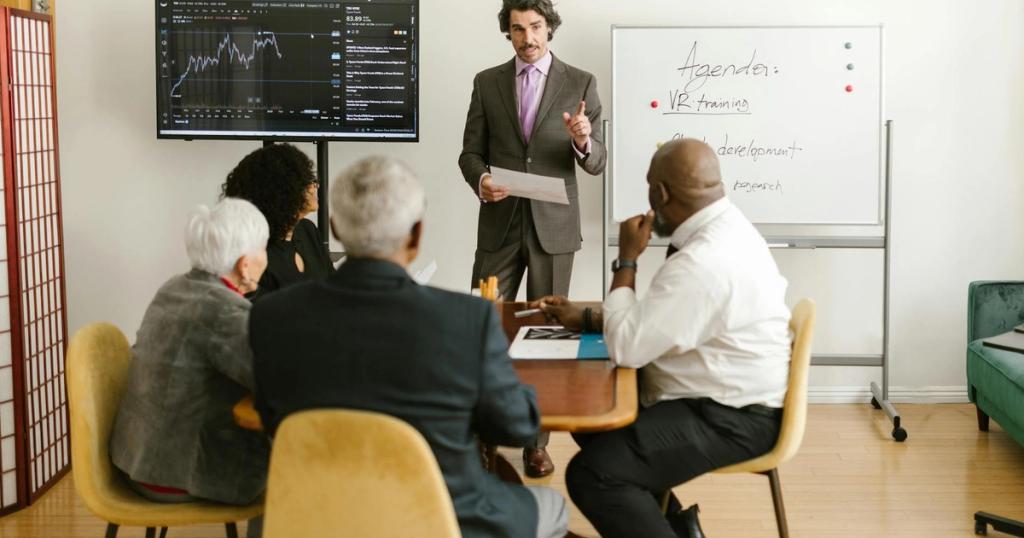A corporate professional presents market data during a team meeting in an office setting.