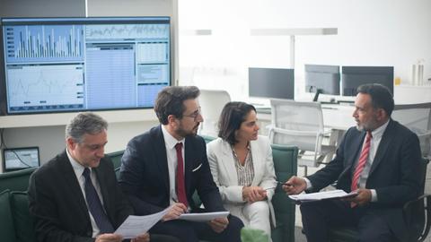 Group of business professionals discussing financial strategies in a modern office setting.