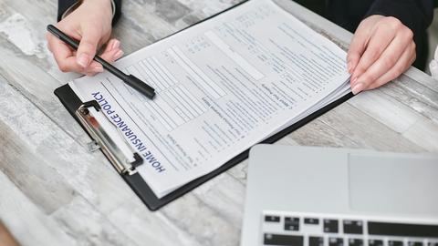 Close-up of hands reviewing a home insurance policy, emphasizing professionalism and finance.