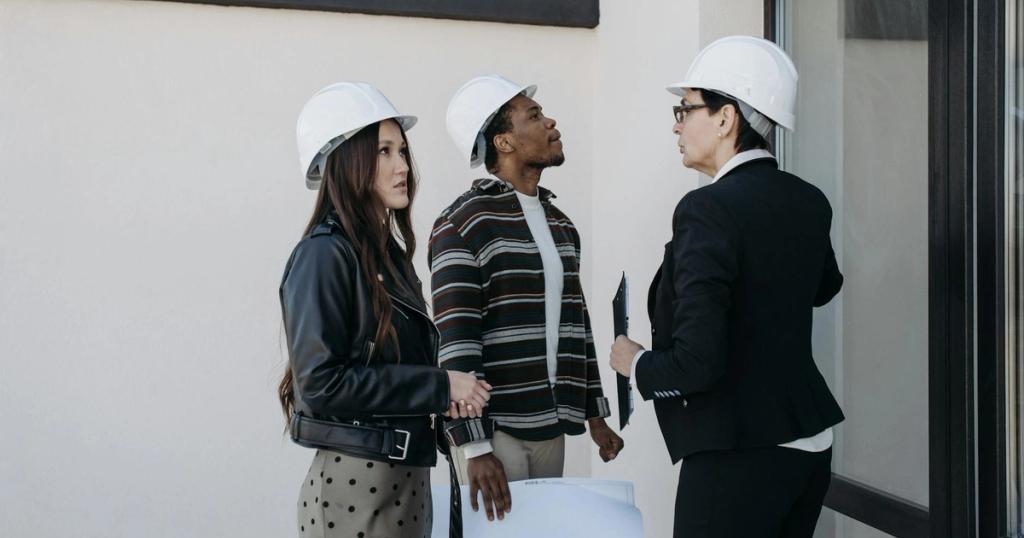 A diverse group of professionals in construction helmets reviewing property plans outdoors.